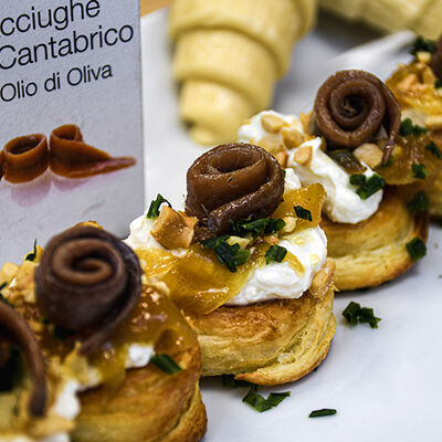 Croissant con nuestras anchoas, crema agria de padano y cebolla caramelizada 